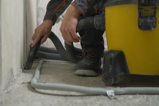 A worker vacuums a concrete floor
